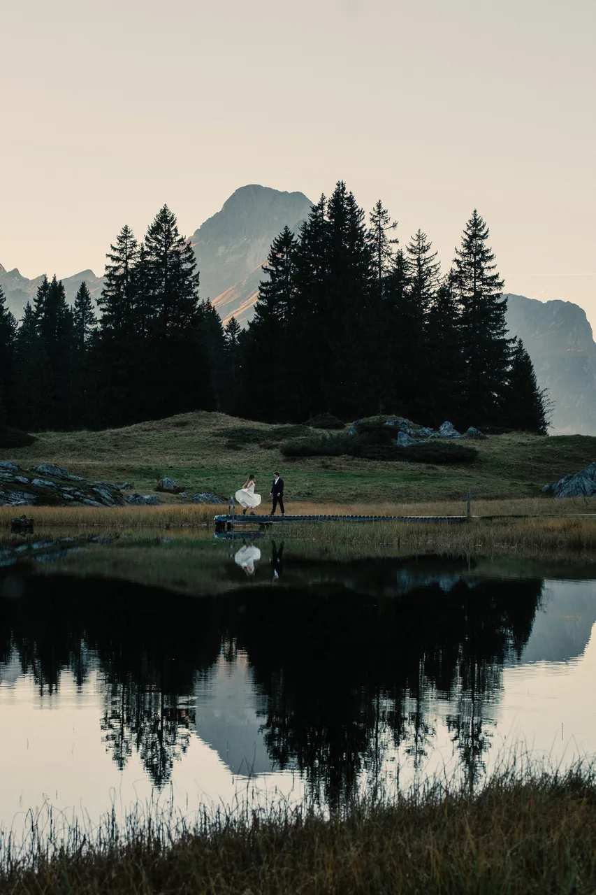 A couple reflected in a still mountain lake in the Austrian Alps