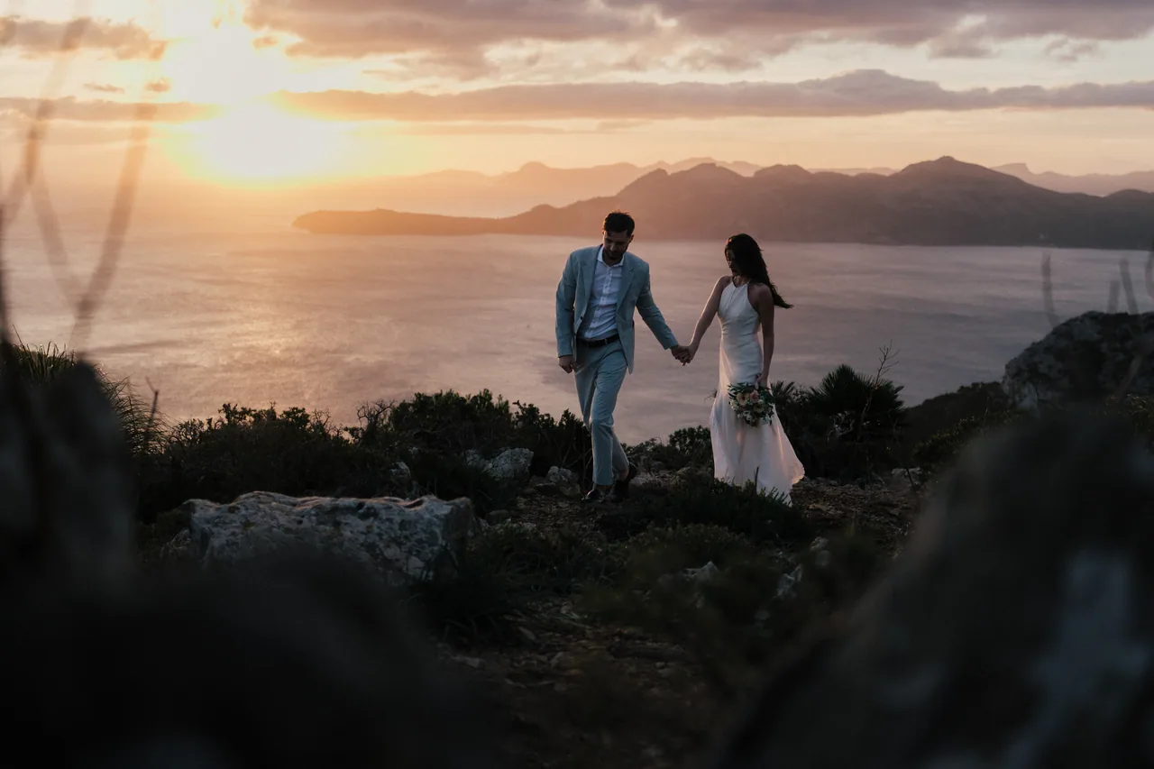 A couple walking a coastal ridge at sunset in Mallorca