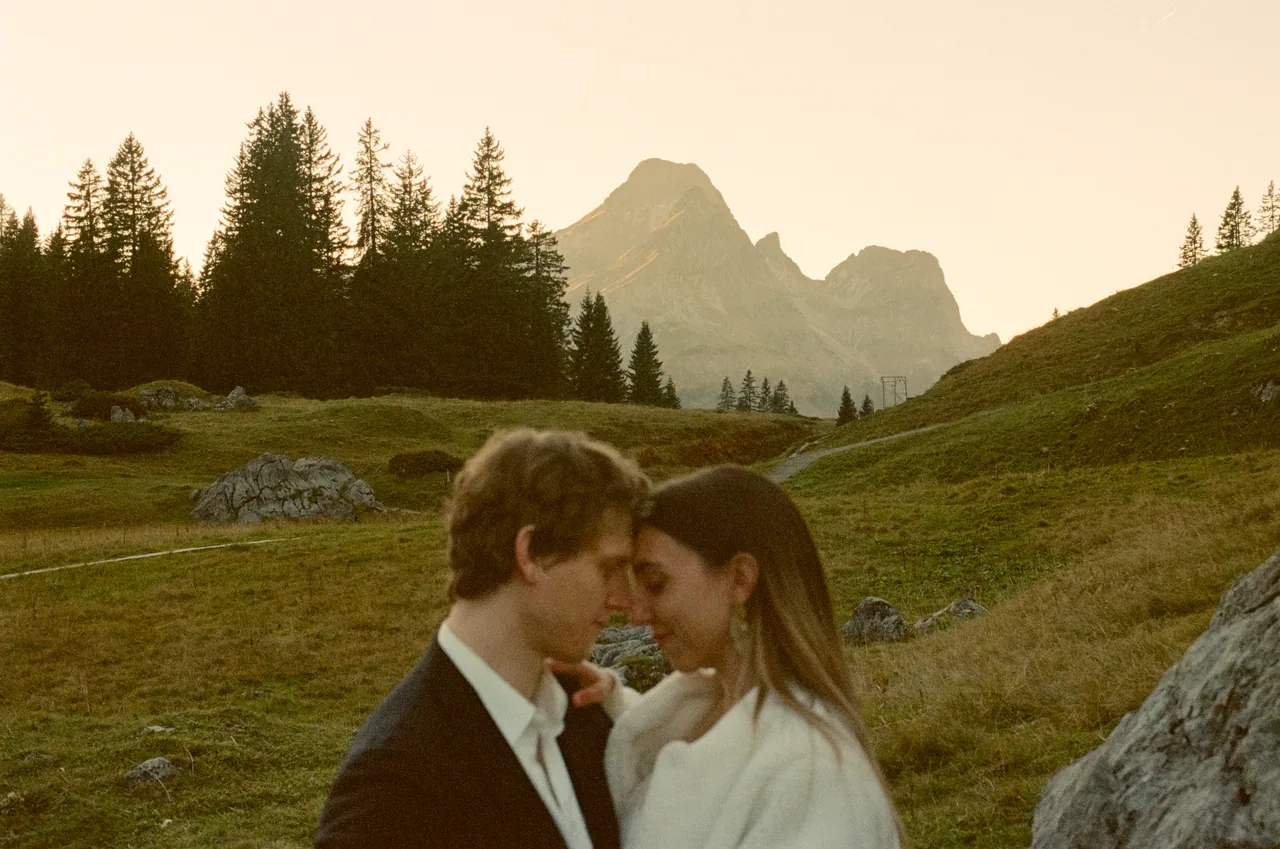 A couple close together in an alpine meadow at dusk, shot on film