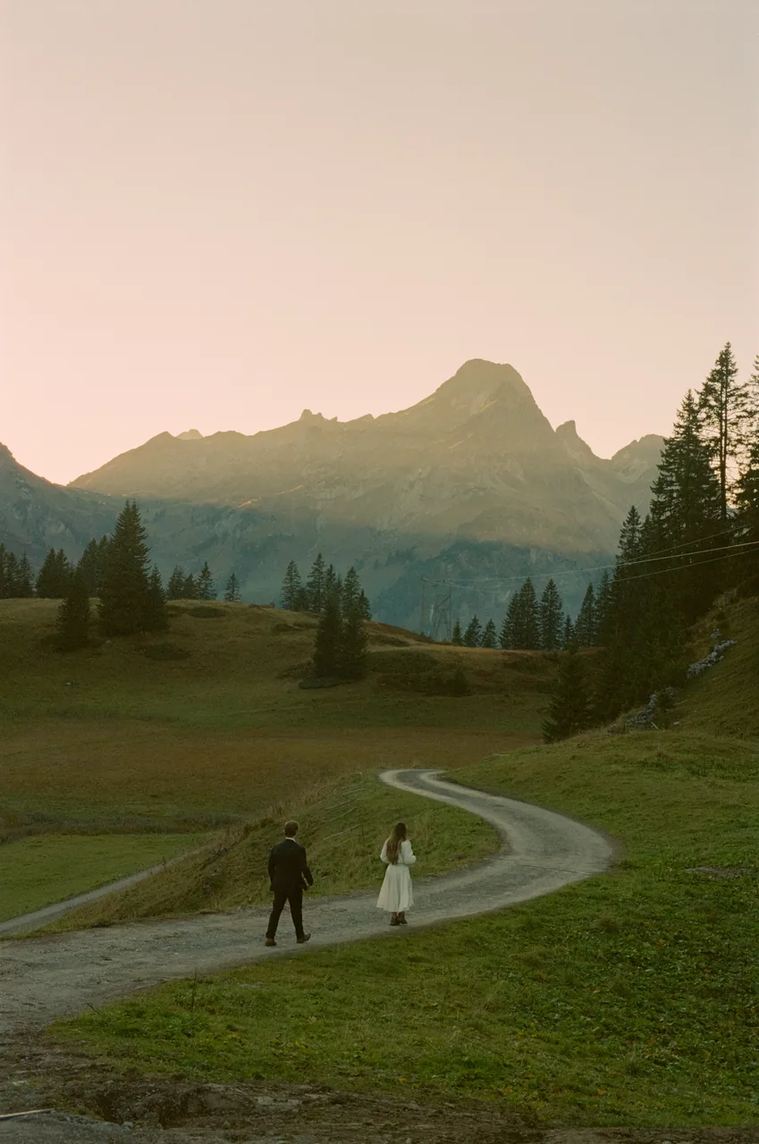 A couple walking a winding mountain road at dusk, shot on film