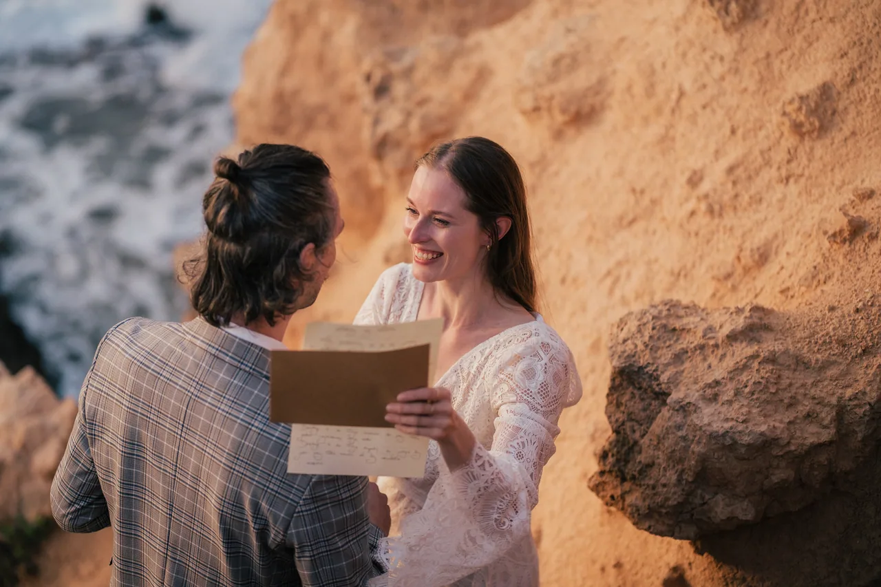 Couple reading their vows from a card on a golden Mallorcan cliff