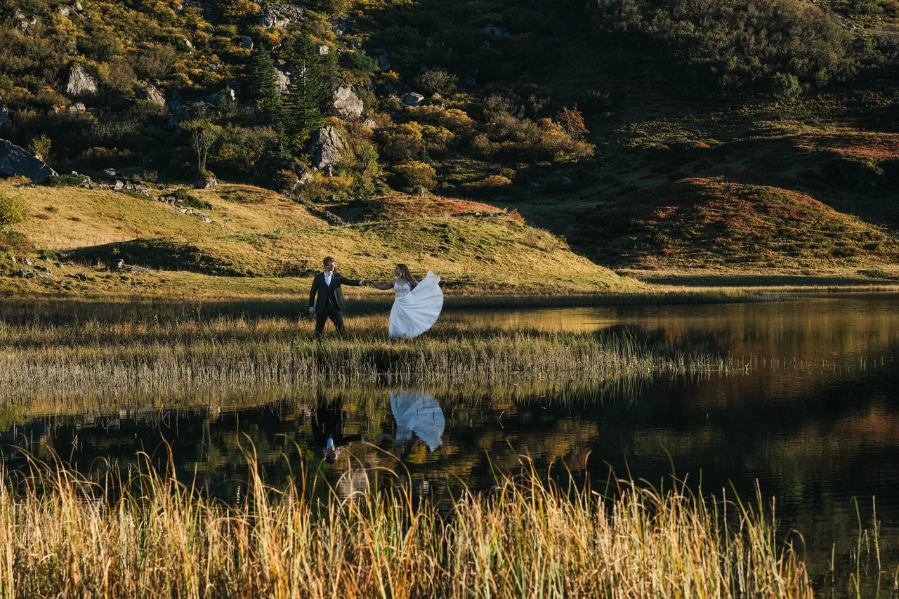 A couple dancing beside a still alpine lake during their symbolic elopement ceremony