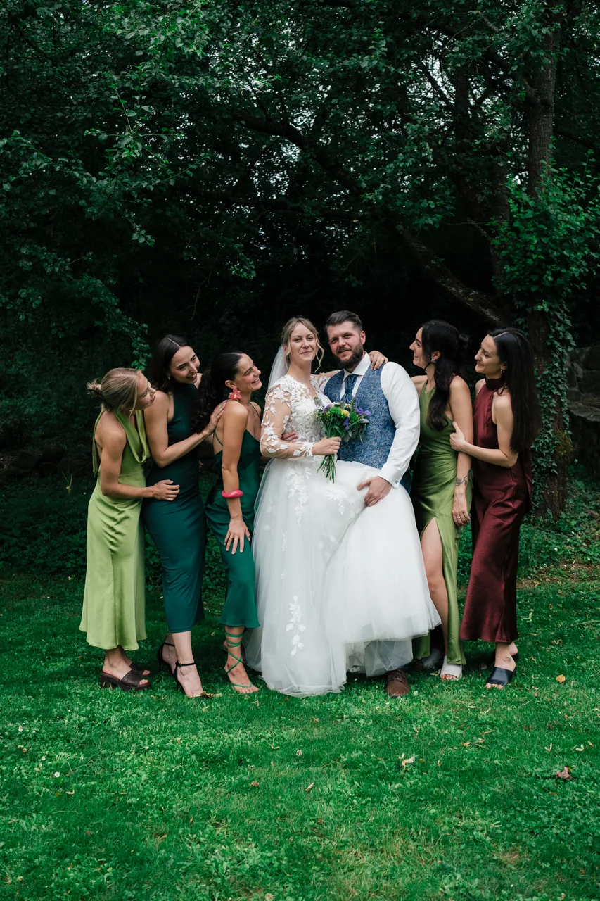 A wedding couple with their bridal party gathered together in a garden