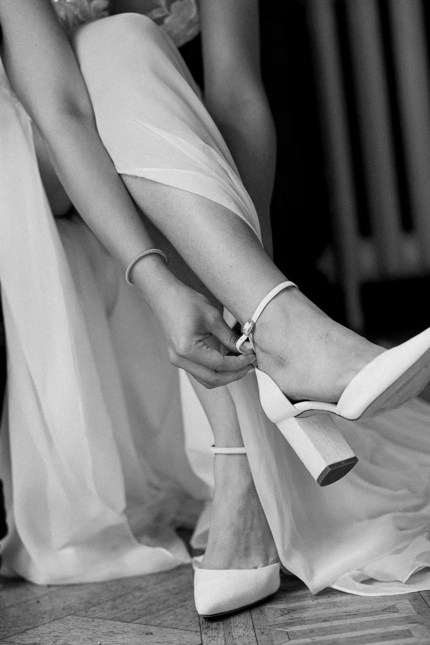 A bride stepping into her wedding shoes, photographed in black and white