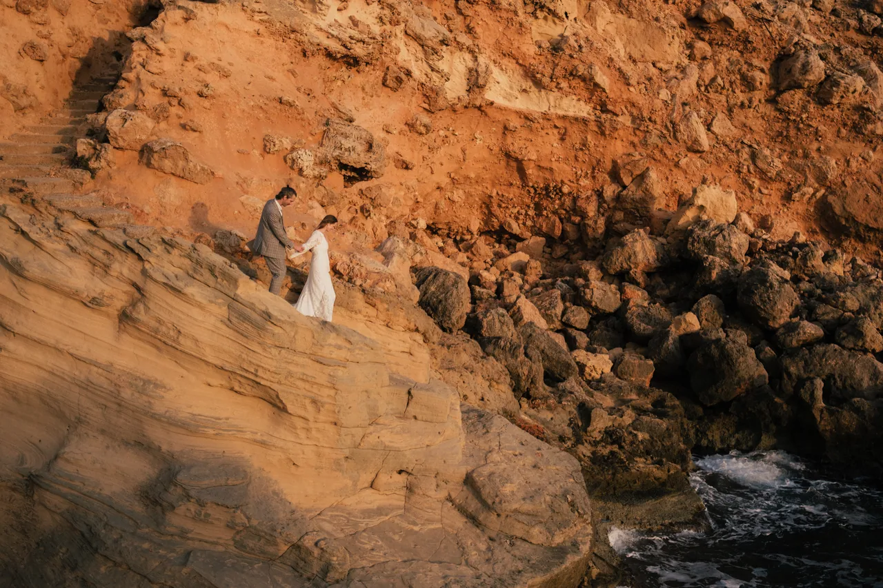 A couple on a golden sea cliff at sunset