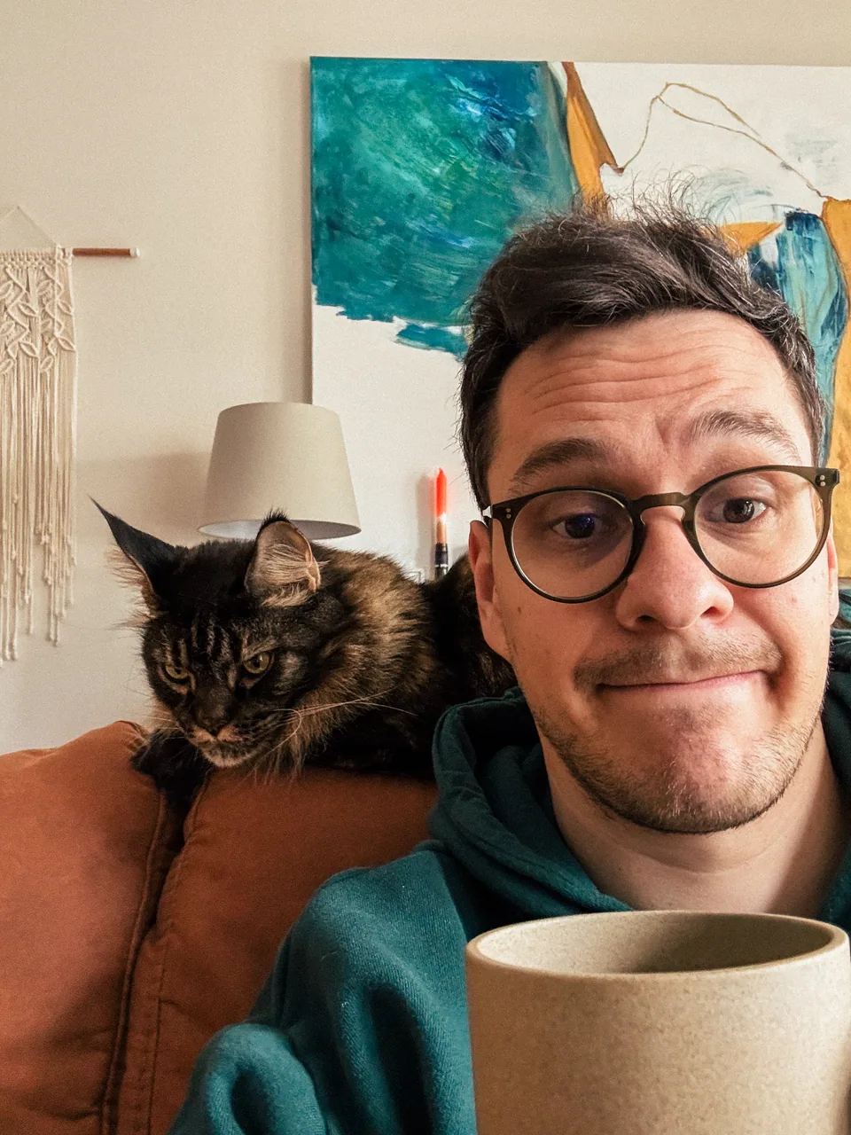 Rainer at home with a coffee and one of the cats